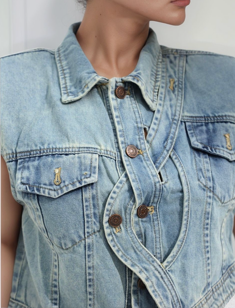 Close‑up of Backcountry Denim Vest showing bronze buttons, pocket detail and light‑blue denim fabric
