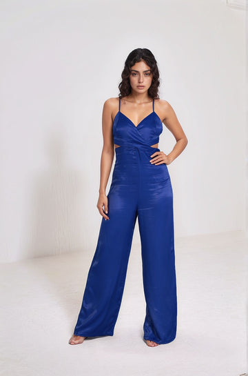 Model wearing blue Cut Out Signature Jumpsuit from the front showcasing wide-leg silhouette and sleek satin texture